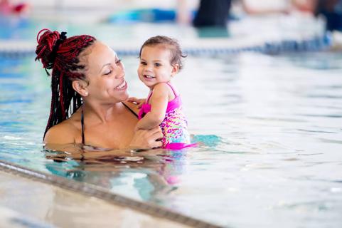 Smiling parent holding smiling baby in a pool