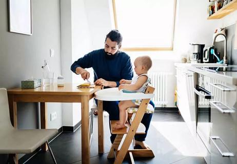 man feeding a baby in a high chair