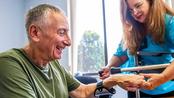 older man doing arm rehabilitation therapy with a healthcare provider