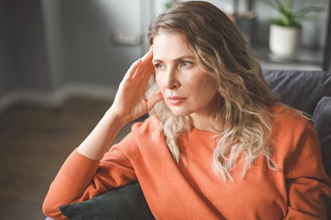 A person sits in an armchair and thoughtfully rests their chin on their hand