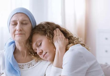 A woman wearing a headscarf comforted by a young girl.