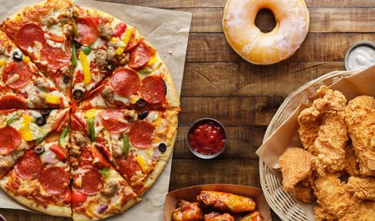 Pizza, donut, chicken wings and fried chicken on wooden table