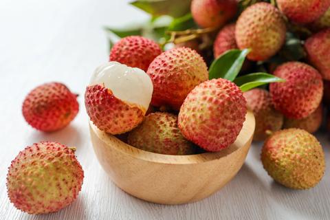 Lychee fruits scattered on table and in bowl