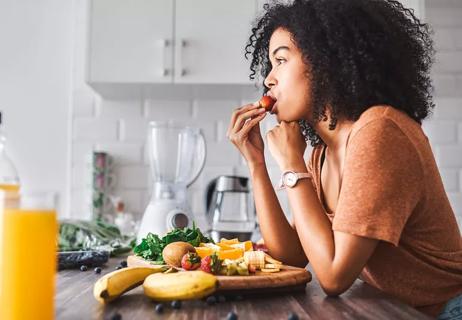 woman eating fruit in kitchen