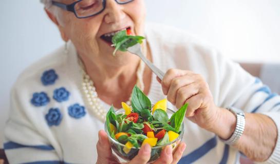 Older person eating a small, colorful salad