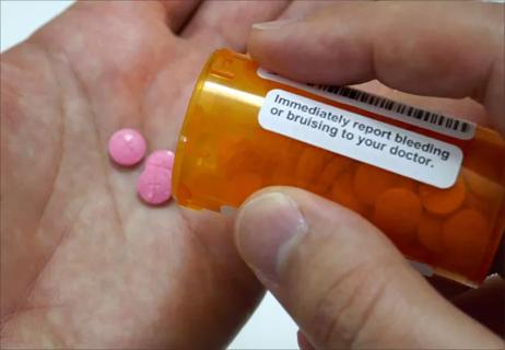 A person holding a prescription bottle with pills.