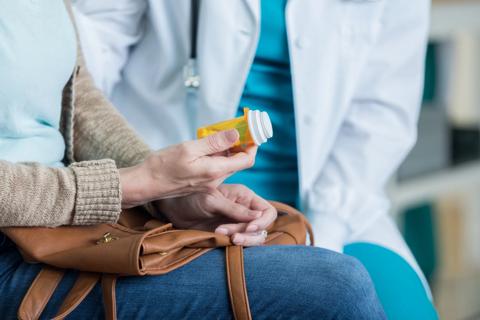 Patient holding prescription medication bottle, talking to healthcare provider