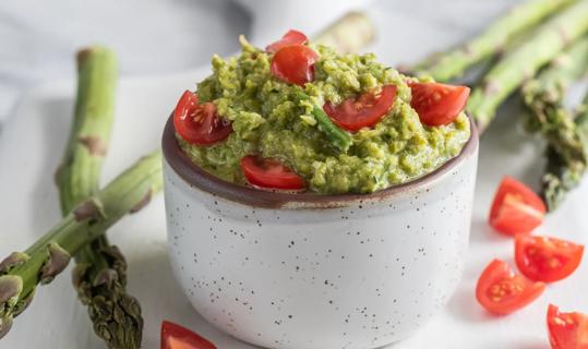 Mexican aparagus dip with diced tomatoes in a small bowl