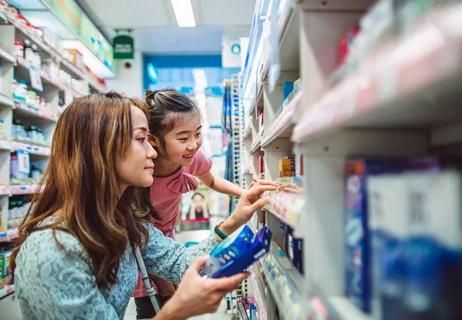 Mother looking at multivitamins for child in a pharmacy.