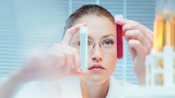 woman in lab holding two vials filled with liquids
