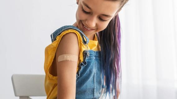 Young smiling teen looking down at bandage on upper arm