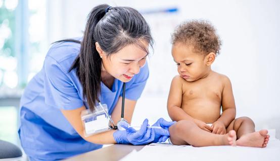 Baby receiving a shot in their leg by healthcare provider