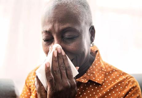 woman sneezing wiping nose