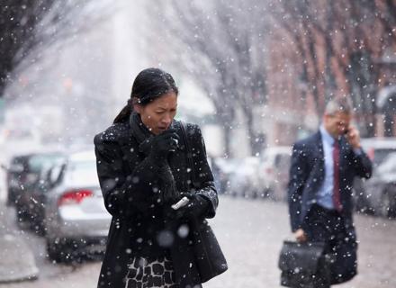 Woman outside in coat during snowy weather covering her mouth