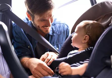 Dad buckling baby into rear facing car seat