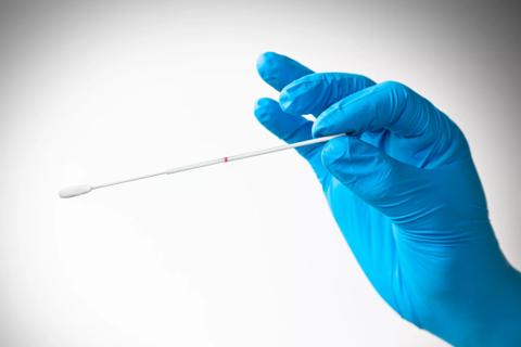 Hand with latex glove holding swab for coronavirus testing