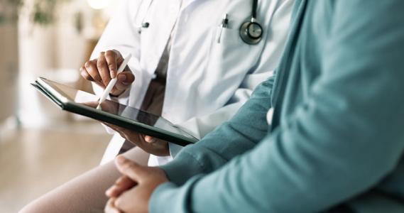 Healthcare provider pointing to tablet while talking to another person