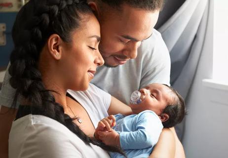 Parents cuddling and admiring their newborn baby.