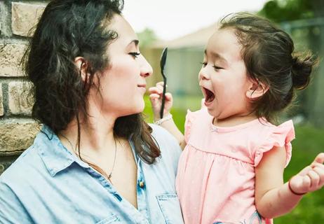 Mother is holding her 1 year old daughter while she talks