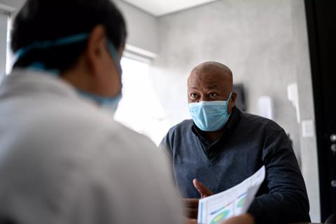 Doctor talking to a patient on medical appointment &#8211; using protective face mask