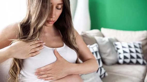 pregnant female feeling her breasts