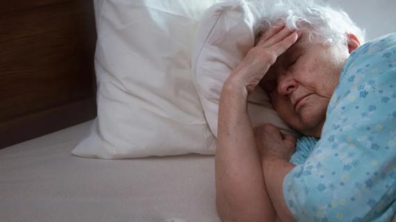 older woman lying with head on pillow looking vaguely unsettled