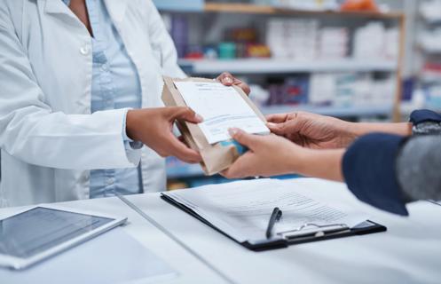 Pharmacist handing medication to patietn