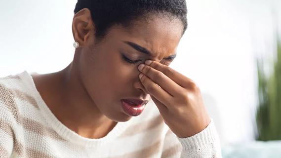 female with fingers pressing on bridge of nose in distress