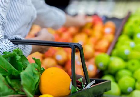 Shopping basket filled with leafy greens and fresh oranges.