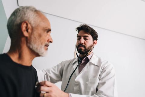 Healthcare provider listening to older person’s heart with stethoscope
