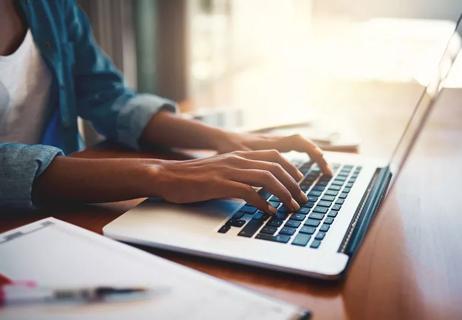 Individual typing on a laptop.