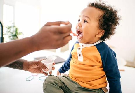 Mother spoon-feeding yogurt to toddler