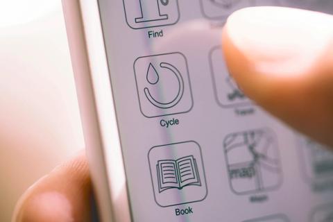 Hand holding smartphone, checking their menstrual cycle app