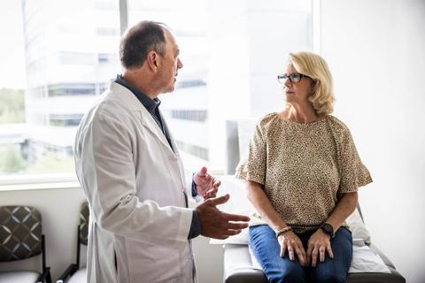 Healthcare provider talking to person sitting on exam table in medical office