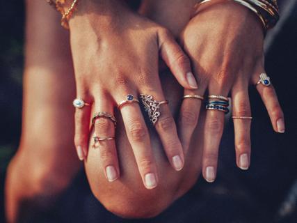 Hands showing many metal rings on the fingers.