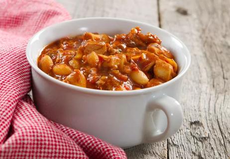 Chicken chili in a white bowl on a natural wood surface.