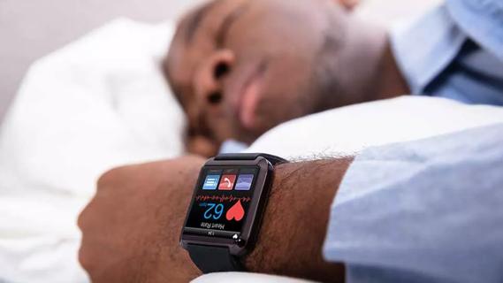 person sleeping in bed with heart rate monitoring watch showing