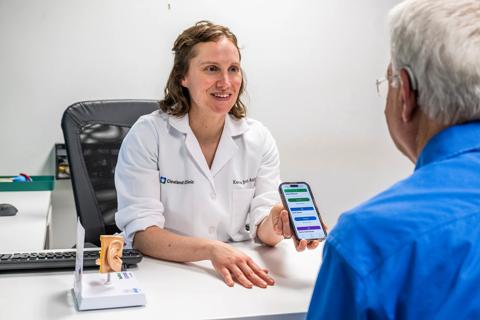 Karen Petter, AuD, showing a patient the auditory training program on a phone.