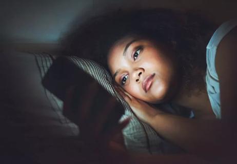 Woman in bed looking at her smart phone