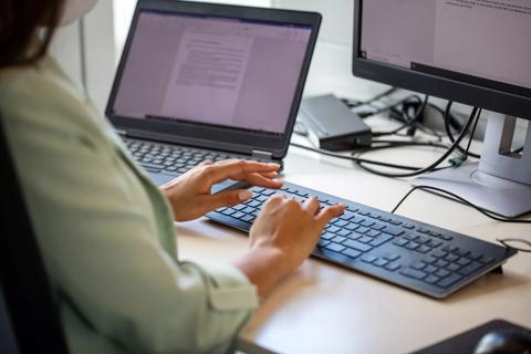 Person typing on keyboard in front of computer screen