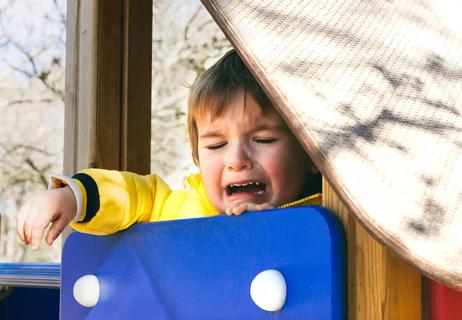 Child cries on a slide at the playground.