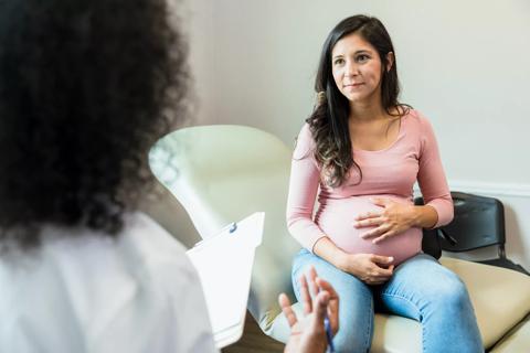 Pregnant person talking with caregiver in medical office