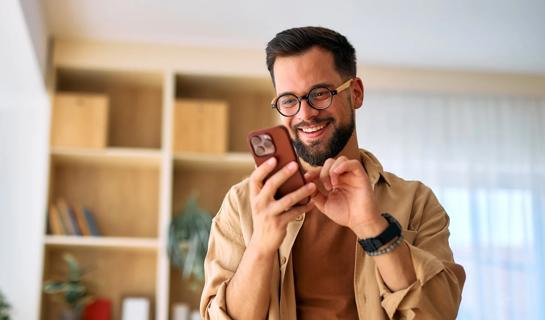Happy person on their smartphone in their living room