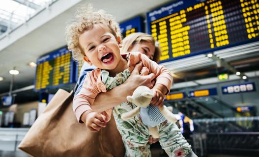 Laughing, happy baby being carried by caregiver in airport