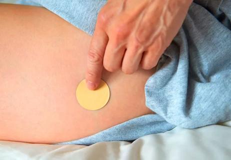 Woman placing transdermal testosterone patch on thigh
