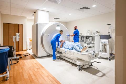 Two healthcare providers situating a patient on an MRI bed, about to receive an MRI