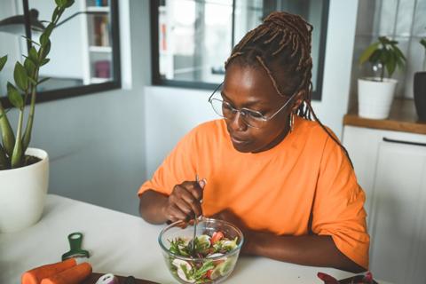 Woman eating a salad at her kitchen counter