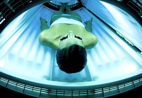 Person lying on their back on a tanning bed.