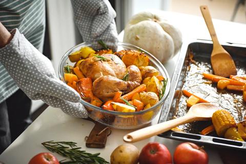 Plating a roasted chicken with vegetables from a baking tray