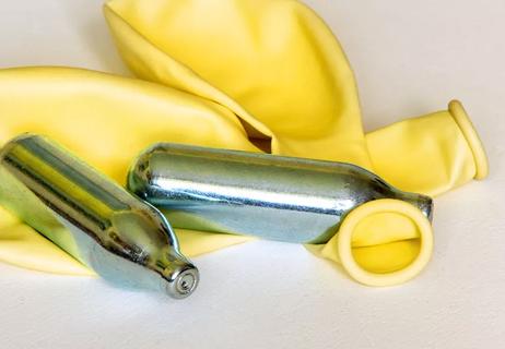 Whippet canisters placed on top of deflated yellow balloons.